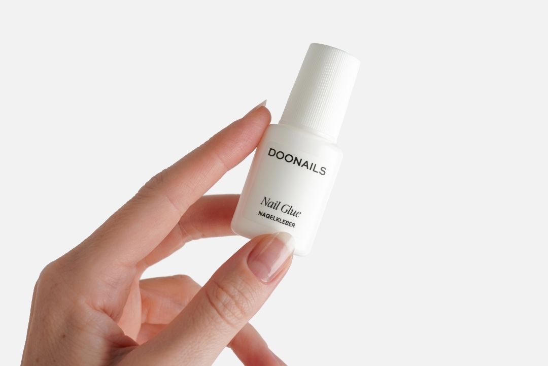 Nagelkleber in der Hand