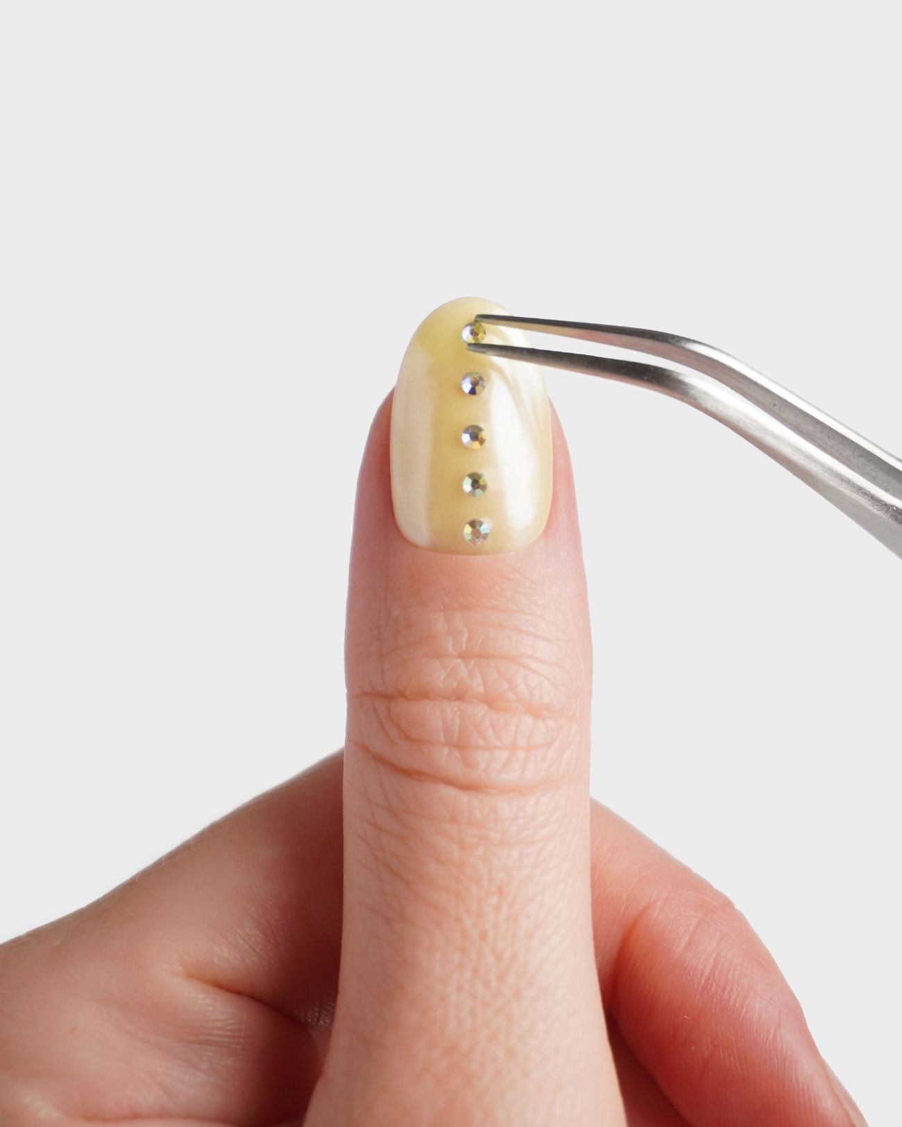 Nailart Pinzette beim Platzieren eines Strasssteines auf den Nagel